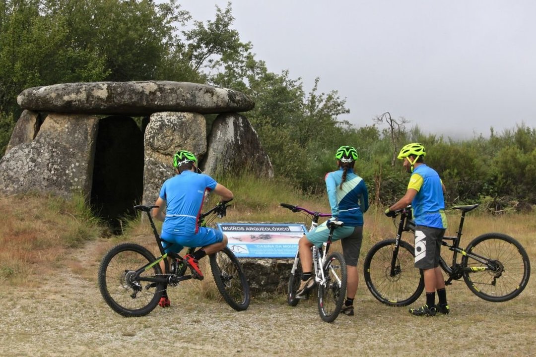 Practicantes de BTT fronte ó dolmen Casuña da Moura na Serra do Xurés.
