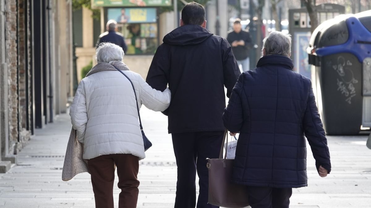 Una persona mayor es acompañada por la calle, en Vigo.
